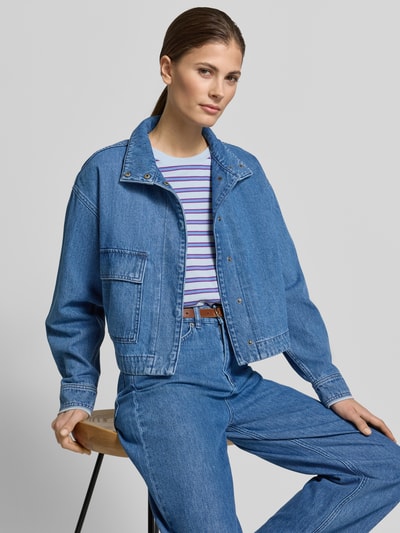 Vrouwenmodel draagt Cropped Denim-Jacke - curated by Tinvcb van SIC, blauwe denim-look, losse fit, opgestikte klepzak, staande kraag, vooraanzicht half totalen.