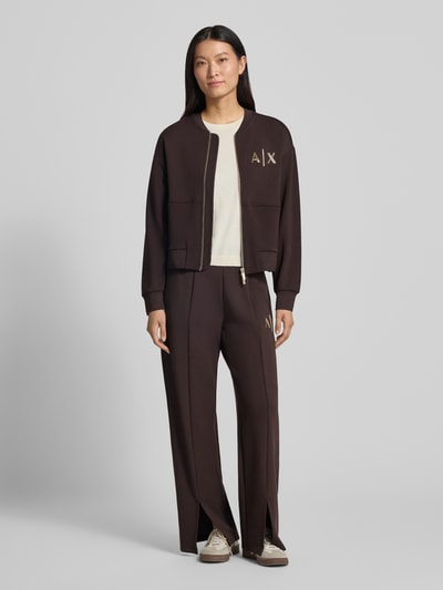 Frauenmodel trägt Sweatjacke mit Label-Print von Armani Exchange, lockere Passform, dunkle Farbe, Zweiwege-Reißverschluss, Ganzkörperansicht von vorne.