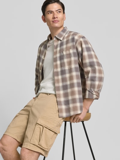 Männermodel trägt Shorts mit Cargotaschen Modell 'NEW 24' von GAP aus Baumwoll-Elasthan-Mix, Regular-Fit, beige, Nahaufnahme Oberschenkel.