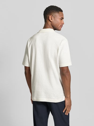 Männermodel trägt Relaxed Fit Poloshirt aus reiner Baumwolle von Marc O'Polo in Uni-Struktur, Polokragen, kurzarm, Ganzkörperansicht Rückansicht.