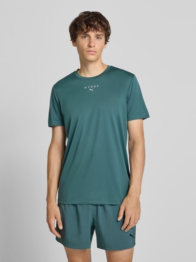 Männermodel trägt Regular Fit Sport-T-Shirt mit Logo-Print Modell 'M PUMA X HYROX' von PUMA, einfarbig grün, glatte Textur, Nahaufnahme Oberkörper, Herren Sport-T-Shirt von PUMA Performance.
