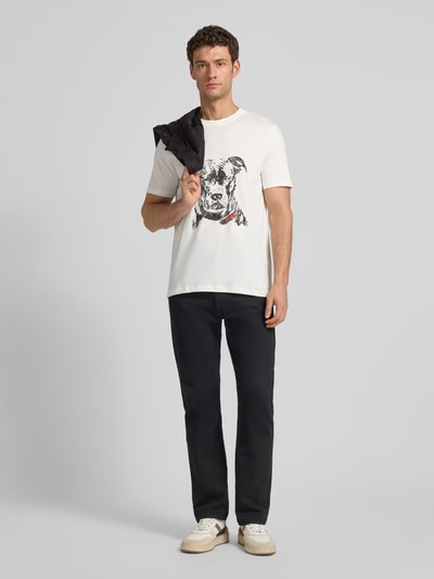 Männermodel trägt Regular Fit T-Shirt aus reiner Baumwolle Modell 'DUBROX' von HUGO in Unifarbe mit Motiv-Print, Ganzkörperansicht von vorne.