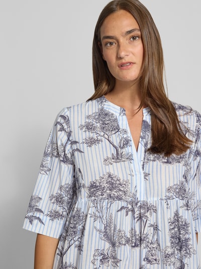 Frauenmodel trägt Minikleid aus Baumwolle im Stufen-Look von Emily Van den Bergh, A-Linie, Allover-Look, V-Ausschnitt, 1/2-Arm, Nahaufnahme Oberkörper.