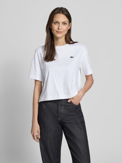 Frauenmodel trägt Oversized T-Shirt aus Baumwoll-Mix von Lacoste mit Optik: Unifarben, Passform: Regular-Fit, Logo-Patch, Kurzarm, Rundhals, Rumpfabschluss: mit Seitenschlitzen, Applikation: Tennis-Print, Material: Baumwoll-Mix, Ganzkörperansicht von vorne.