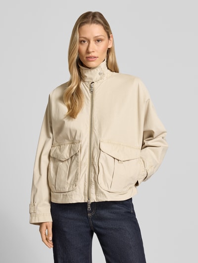 Modelka kobieca ma na sobie Jacke mit Zweiwege-Reißverschluss od Blonde No. 8, beżowa bawełna, luźny krój, długość tyłu 57 cm, szerokość ramion 42 cm, szerokość klatki piersiowej 80 cm, długość rękawa 60 cm, widok całej sylwetki z przodu.