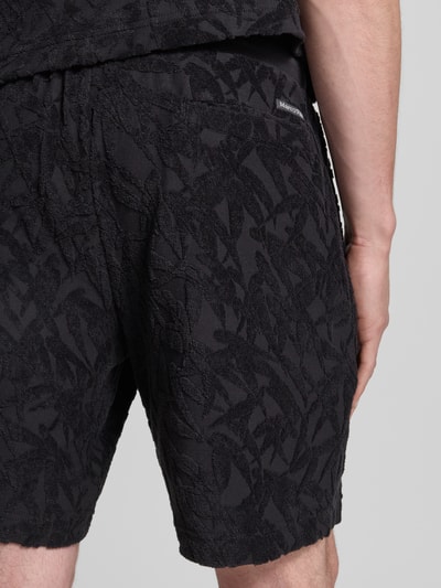 Männermodel trägt Regular Fit Sweatshorts aus reiner Baumwolle von Marc O'Polo mit floralem Allover-Muster, Frottee-Jersey, Label-Patch, Nahaufnahme Rückansicht