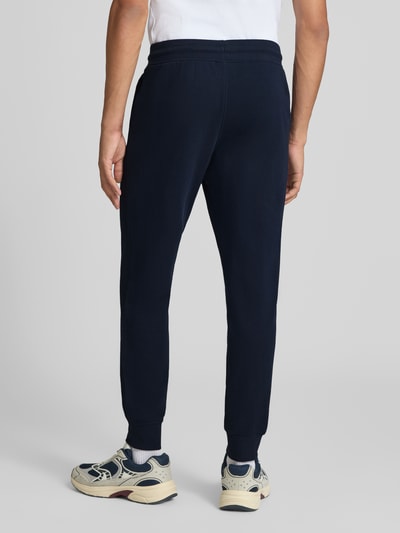 Männermodel trägt navyfarbene sweatpants mit labelprint Modell 'GORDON' von JACK & JONES, los model, steekzakken, binnenbeenlengte maat M 77 cm, elastische band met tunnelkoord, ganzkörperansicht rückansicht