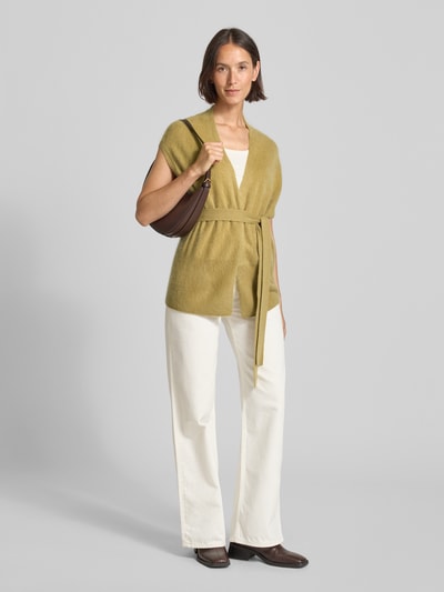 Modelka nosi Loose Fit Strickweste aus Kaschmir-Woll-Mix od HERZENS, kolor oliwkowy, bez rękawów, pasek, długość pleców 68 cm, pełen widok z przodu.