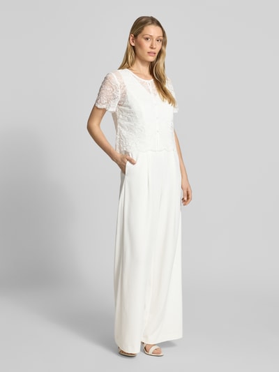 Modelka nosi Regular Fit Jumpsuit mit Spitzenbesatz od Vera Mont z elastycznej mieszanki materiałów, cekinowe obszycie, krój regular fit, z krótkim rękawem, listwa guzikowa, okrągły dekolt, całkowita długość 157 cm, szerokość w rozmiarze 36: 47 cm, długość tyłu 50 cm, długość rękawów 20 cm, długość wewnętrzna nogawki 81 cm, widok całej sylwetki z przodu.