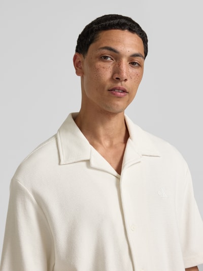 Männermodel trägt Relaxed Fit Freizeithemd aus reiner Baumwolle von Calvin Klein Jeans in Optik: Unifarben mit Logo-Stitching, Nahaufnahme Oberkörper.