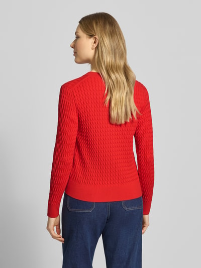 Frauenmodel trägt Slim Fit Strickjacke aus reiner Baumwolle von Tommy Hilfiger, Optik: Unifarben, Zopfmuster, Ganzkörperansicht Rückansicht.