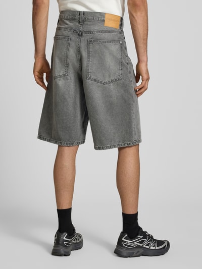 Männermodel trägt Jeansshorts im Used-Look mit Eingrifftaschen von REVIEW, graue Reine Baumwolle, Relaxed-Fit, Ganzkörperansicht Rückansicht.