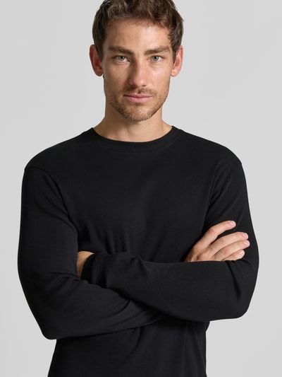 Męski model nosi Slim Fit Longsleeve aus reiner Baumwolle Model 'Enil' od DRYKORN, czarny, fakturowany wzór, okrągły dekolt, krój slim fit, Długość tyłu 67 cm, Długość rękawów 69 cm, z przodu, zbliżenie na górną część ciała.