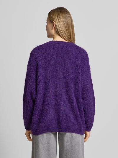 Frauenmodel trägt Cardigan mit V-Ausschnitt Modell 'EAST' von American Vintage in Lila, Material-Mix mit Alpaka-Anteil, Ganzkörperansicht Rückansicht.