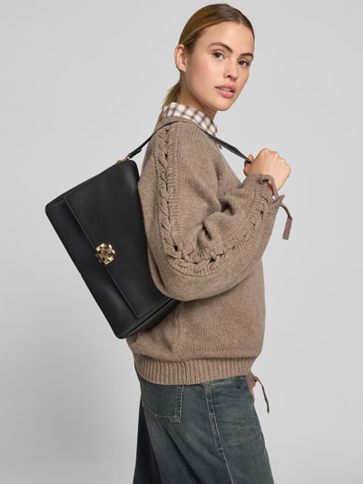 Frauenmodel trägt Shoulder Bag mit Logo-Detail von Tory Burch, Schwarz, glatte Struktur, Magnetverschluss, abnehmbarer Schulterriemen, Hauptfach mit Überschlag, innen Reißverschlussfach, Breite 33 cm, Länge 23 cm, Tiefe 13 cm, Ganzkörperansicht Rückansicht.