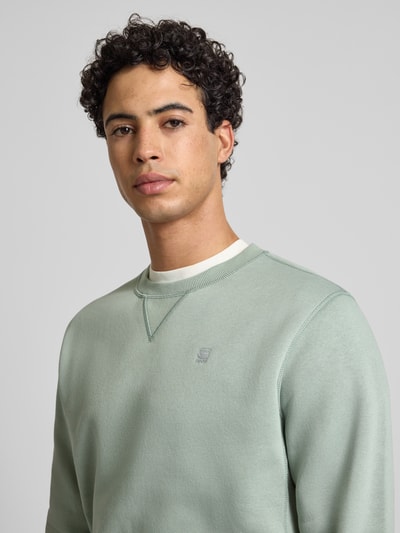 Męski model nosi bluzę z mieszanki bawełny Premium core od G-Star Raw, prosty krój, okrągły dekolt, wyhaftowane logo, miękka faktura. Nahaufnahme Oberkörper.