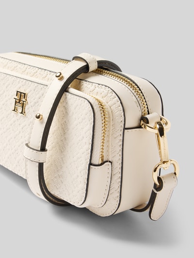 Produktfoto, cremefarbene Umhängetasche mit abnehmbarem Schulterriemen von Tommy Hilfiger, Allover-Prägung, Logo-Detail, goldfarbener Reißverschluss, RFID-Schutz, Haupt- und Seitenfach, unifarbene Optik, Tragehenkel