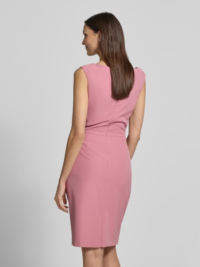 Modelka nosi Knielanges Cocktailkleid mit Raffungen von Vera Mont w różowym kolorze, prosty materiał z elastycznym dodatkiem, długość do kolan, widoczne marszczenia, szerokość w rozmiarze 36: 42 cm, długość na plecach w rozmiarze 36: 99 cm, widok całej sylwetki od tyłu.