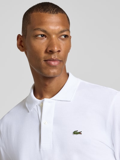 Männermodel trägt Regular Fit Poloshirt aus reiner Baumwolle von Lacoste in Weiß mit glatter Textur, Nahaufnahme Oberkörper, Herren Poloshirt von Lacoste.