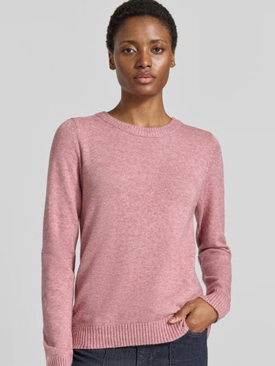 Frauenmodel trägt Strickpullover aus Viskose-Mix von VILA in Rosa, taillierte Passform, gerippter Rundhalsausschnitt, Nahaufnahme Oberkörper.