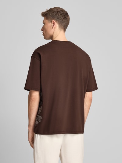 Männermodel trägt Loose Fit T-Shirt mit Stitchings von Scotch & Soda, braun, Reine Baumwolle, Rundhalsausschnitt, Rückenlänge 71 cm, Ganzkörperansicht Rückansicht.