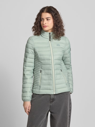 Frauenmodel trägt Steppjacke mit Logo-Stitching Modell 'FUJI' von Superdry in Mint, Gerader-Schnitt, Stehkragen, Reißverschlusstaschen, Ganzkörperansicht von vorne. Rückenlänge 62 cm, Schulterbreite 40 cm, Brustweite 50 cm, Ärmellänge 69 cm bei Größe S.
