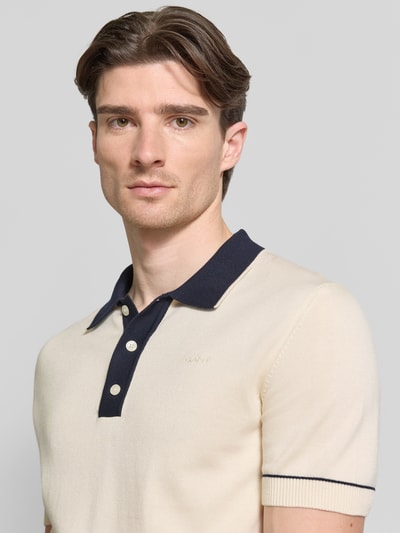 Männermodel trägt Slim Fit Poloshirt mit Logo-Stitching von Gant in Beige mit dunkelblauem Kragen, Baumwoll-Modal-Mix, Nahaufnahme Oberkörper.