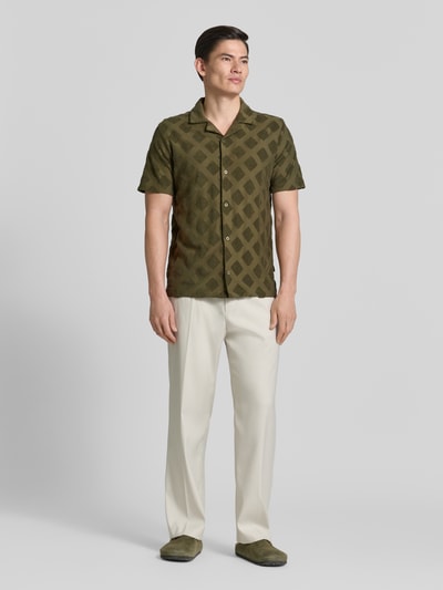 Männermodel trägt Slim Fit Poloshirt mit Strukturmuster von Fynch-Hatton aus Baumwoll-Mix, Reverskragen, Kurzärmelig, Ganzkörperansicht von vorne.
