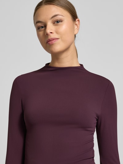 Frauenmodel trägt Slim Fit Longsleeve mit Stehkragen von Fabletics in dunklem Lila, elastischer-Material-Mix, Langärmelig, Nahaufnahme Oberkörper.