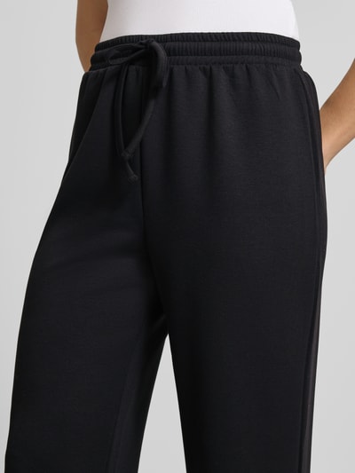 Frauenmodel trägt Regular Fit Sweatpants mit Viskose-Anteil Modell 'TALIA' von Pieces, unifarben schwarz, Nahaufnahme Hüfte bis Oberschenkel.