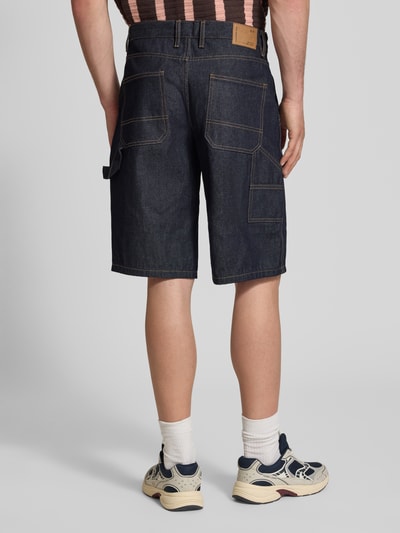Männermodel trägt Baggy Fit Jeansshorts Modell 'ARAGON' von Redefined Rebel aus Reine Baumwolle mit Eingrifftaschen, Dunkelblau, Ganzkörperansicht Rückansicht. Bundweite bei Größe M: 50 cm, Innenbeinlänge: 33 cm.