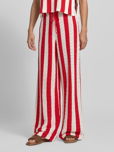 Frauenmodel trägt Strickhose mit Label-Detail und elastischem Bund von Karo Kauer aus Baumwoll-Mix in Rot und Creme mit Loose-Fit, Kordelzug, sichtbarer Struktur, Bundweite 38 cm, Innenbeinlänge 76 cm, Ganzkörperansicht von vorne.