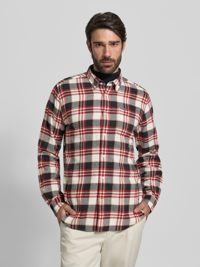 Męski model nosi Slim Fit Freizeithemd aus reiner Baumwolle od Barbour, wzór kratka, długi rękaw, bawełna, guzik, widok całego ciała z przodu.
