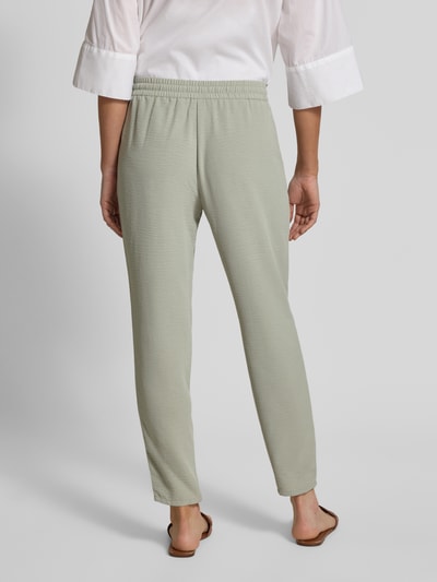 Frauenmodel trägt Jogpants mit elastischem Bund und Eingrifftaschen von Christian Berg Woman in hellem Grün, Schlupfhosen-Design, Slim Fit, Bundweite bei Größe 36: 38 cm, Innenbeinlänge bei Größe 36: 72 cm, Ganzkörperansicht Rückansicht.