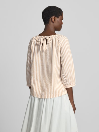 Frauenmodel trägt Loose Fit Kurzarmbluse aus Viskose-Baumwoll-Mix von s.Oliver RED LABEL in Beige-Weiß mit feinen Streifen, Ganzkörperansicht Rückansicht.
