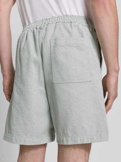 Männermodel trägt Regular Fit Shorts aus Baumwoll-Mix Modell 'SANDREW' von BOSS Orange, efekt: jednolity kolor, jednolita faktura twill-jacquard, naszywka z logo, szlufki na pasek, zapięcie na guzik i kryty zamek błyskawiczny, kieszeń z tyłu, boczne wpuszczane kieszenie, wykończenie: mieszanka bawełny; Ganzkörperansicht Rückansicht.