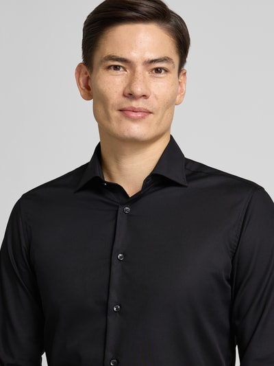 Männermodel trägt Slim Fit Business-Hemd mit Knopfleiste von ETERNA aus reiner Baumwolle, Kentkragen, schwarze Farbe, Nahaufnahme Oberkörper.