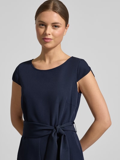 Kobiece modelka nosi Kombinezon mit Bindegürtel von Christian Berg Woman Selection, mieszanka materiałów z dodatkiem streczu, krój regular fit, okrągły dekolt, wiązany pasek, szerokość w rozmiarze 36: 37 cm, długość tyłu w rozmiarze 36: 39 cm, całkowita długość w rozmiarze 36: 130 cm, długość rękawów w rozmiarze 36: 7 cm, długość wewnętrzna nogawki: 61 cm, gładka tekstura, ciemnogranatowy kolor, zbliżenie na górną część ciała