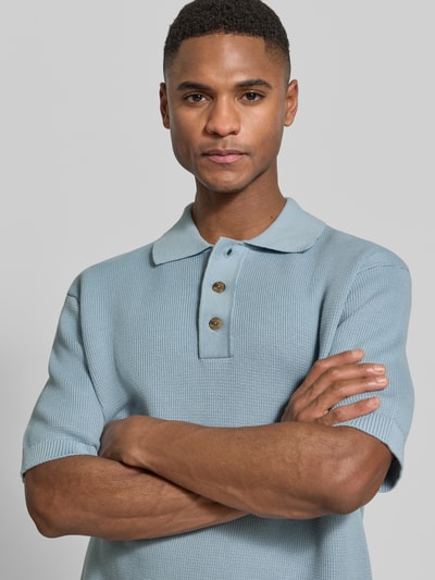 Männermodel trägt Relaxed Fit Poloshirt aus reiner Baumwolle Modell 'DANE' von SELECTED HOMME in blauer Strickoptik, Nahaufnahme Oberkörper.