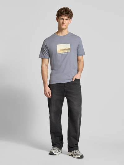 Männermodel trägt T-Shirt mit Rundhalsausschnitt Modell 'JORNORREBRO' von Jack & Jones aus reiner Baumwolle in Grau, gerader Schnitt, Ganzkörperansicht von vorne.