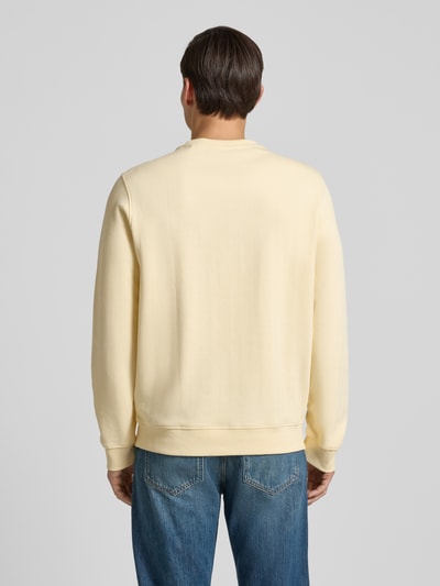 Männermodel trägt Sweatshirt mit Logo und Rundhalsausschnitt von Guess in Beige, Baumwolle, Regular Fit, Rückenansicht, Ganzkörperansicht Rückansicht.