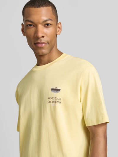 Männermodel trägt T-Shirt mit rückseitigem Motiv-Print von MCNEAL in Gelb, gerade Form, Bio-Baumwolle, Nahaufnahme Oberkörper.