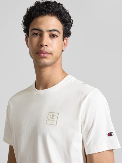 Männermodel trägt T-Shirt mit Logo und Rundhalsausschnitt von CHAMPION aus Reine Baumwolle, Regular-Fit, Rückenlänge bei Größe M 68 cm, Nahaufnahme Oberkörper.