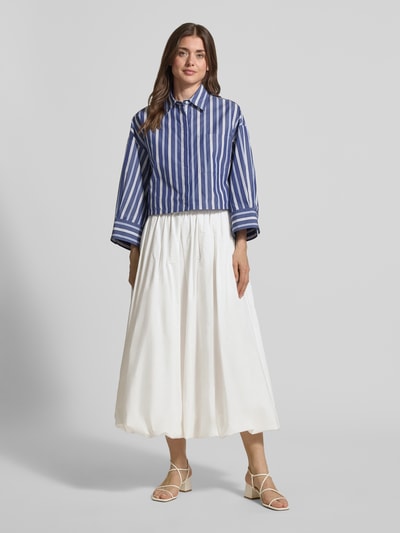 Frauenmodel trägt ausgestellten Maxi-Rock aus reiner Baumwolle Modell 'NUVOLE' von Weekend Max Mara, uni Weiß, Regular Fit, gerade Ballon-Saum, mit seitlichen Eingrifftaschen, Ganzkörperansicht von vorne.