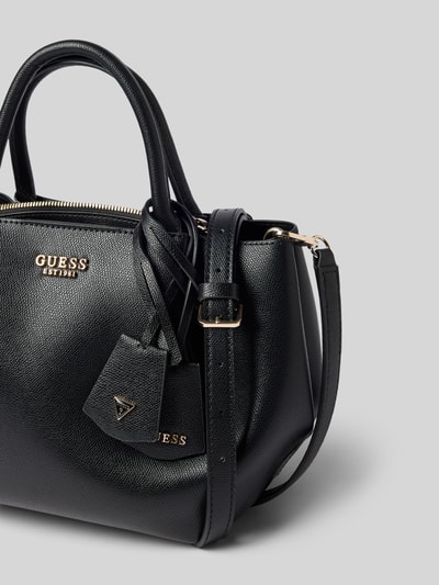 Produktfoto, schwarze Handtasche in Leder-Optik Modell 'Amorette' von GUESS mit Logo-Detail, Magnetverschluss und abnehmbarem Riemen vor grauem Hintergrund