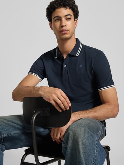 Männermodel trägt Slim Fit Poloshirt mit Logo-Stitching Modell 'Dunda' von G-Star Raw, Baumwoll-Mix, Polokragen, Nahaufnahme Oberkörper.
