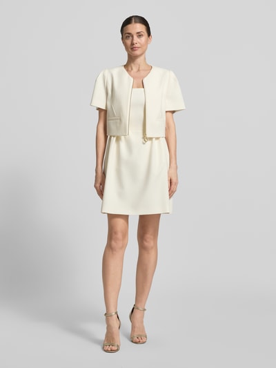 Frauenmodel trägt Slim Fit Kurzblazer mit Viskose-Anteil Modell 'Ambelle' von HUGO in creme, strukturierter Jacquard, Ganzkörperansicht von vorne.
