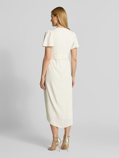 Frauenmodel trägt Cocktailkleid in Wickel-Optik mit Schmetterlingsärmeln von Christian Berg Cocktail, cremefarben, Satin, taillierter Schnitt, Midikleid, V-Ausschnitt, Bindegürtel, verlängerter Rücken, rückseitiger Haken- und Reißverschluss, Ganzkörperansicht Rückansicht.