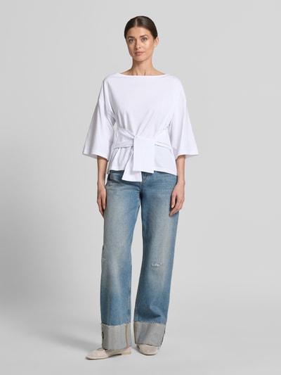 Frauenmodel trägt Shirt mit U-Boot-Ausschnitt Modell 'Dajana' von GUIDO MARIA KRETSCHMER WOMAN aus Reine Baumwolle, taillierter Schnitt, 3/4-Arm, Raffung, Rückenlänge 56 cm bei Größe 36, weiße Farbe, glatte Textur, Ganzkörperansicht von vorne.