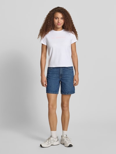 Frauenmodel trägt T-Shirt mit Print und Rundhalsausschnitt von REVIEW aus Baumwoll-Elasthan-Mix, Regular-Fit, weiße Farbe, Rückenlänge 51 cm, Ganzkörperansicht von vorne.